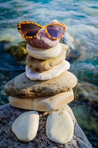 海石堆在海洋上，形成一个戴眼镜的男人，以蓝色的海水为背景。海滨度假，夏季旅游旺季。图片下载