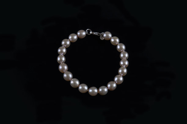 真正的圆形珍珠手镯在象牙色的黑色背景图片下载