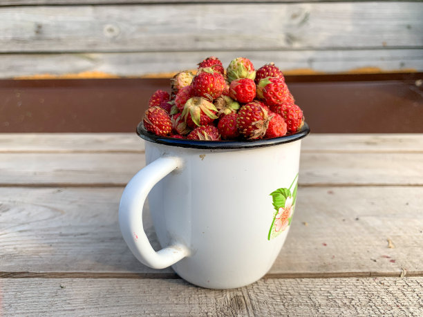 木质背景上的白杯子里装着新鲜草莓。适当的营养，维生素，草莓的收获。图片下载