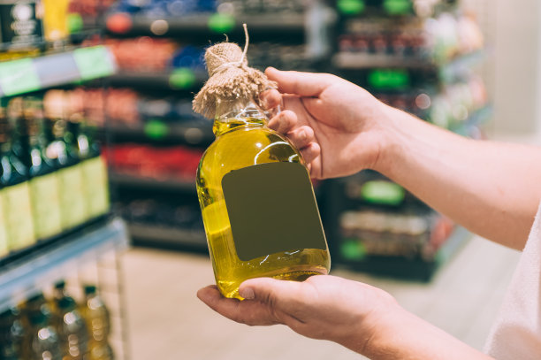 一个男人手里拿着一瓶橄榄油。概念人在商店中选择一种产品。图片下载