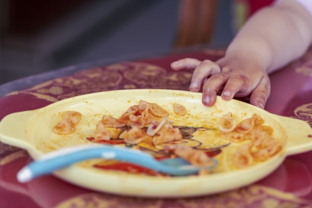 蹒跚学步的婴儿拉到自己的意大利面盘子，特写图片下载