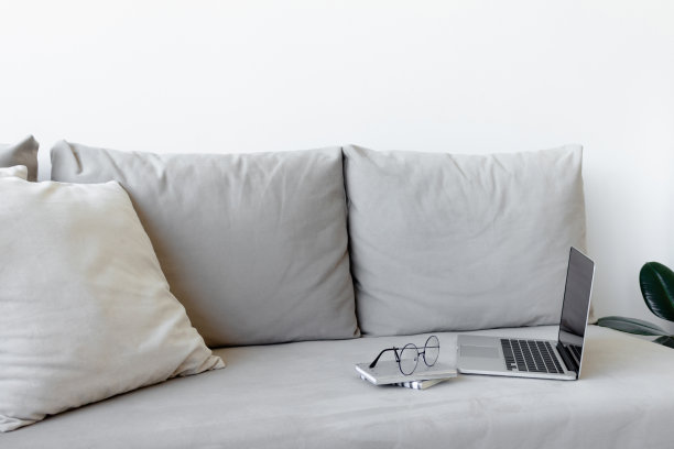 灰色沙发上放着笔记本电脑，眼镜，记事本。图片下载