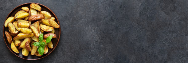 油炸土豆块，盐和大蒜在一个盘子在黑色背景。从以上观点。图片下载