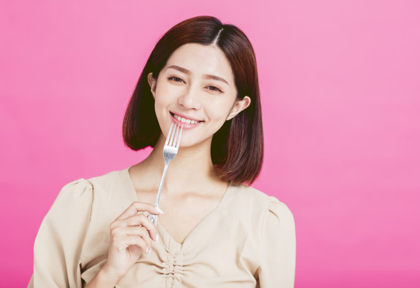 美丽的年轻女子拿着叉子品尝食物图片下载