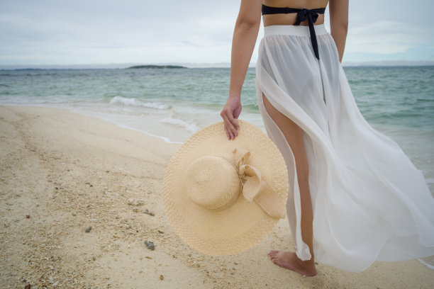 一名亚洲女子在晴朗的日子穿着比基尼和海帽在沙滩上图片下载
