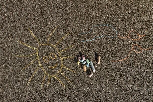 简单的粉笔画微笑的太阳，云彩和鸟在人行道上图片下载