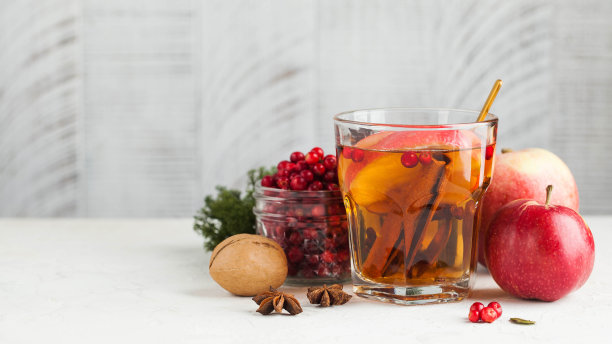 横幅秋天食物照片与热茶肉桂，柠檬，苹果，浆果和香料在一个透明的杯子。副本的空间。图片下载