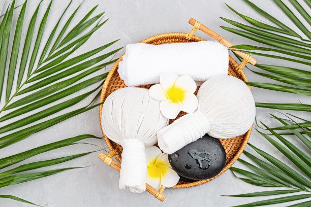 Spa按摩芳香疗法身体护理背景。灰色的混凝土桌上放着草药球、化妆品、毛巾和热带树叶。俯视图，平铺，头顶，拷贝空间。美容保健理念图片下载