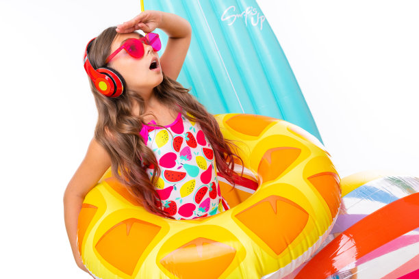 酷酷的女孩，长着十字架般的头发，戴着墨镜，穿着泳衣，站在橡胶圈里的充气床垫旁边，向一边看图片下载