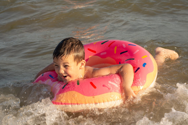 一个阳光明媚的日子，一个5岁的小男孩在一个甜甜圈形状的救生圈里洗澡。图片下载