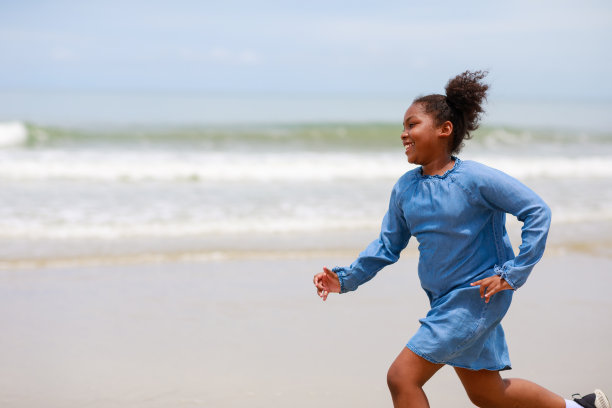 非洲女孩在海滩上跑步。图片下载