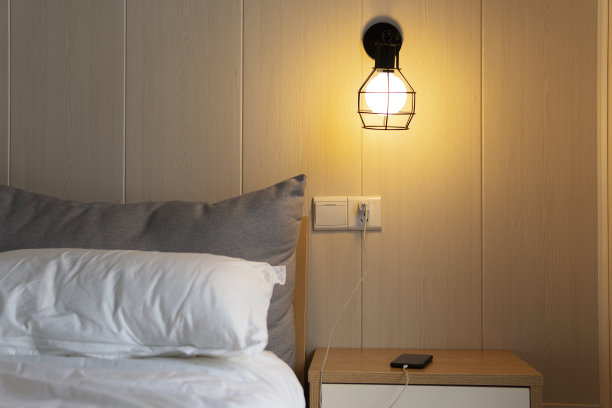 一个舒适的房间，一个舒适的床，一个床头柜和一个手机在温和的灯光下充电酒店图片下载