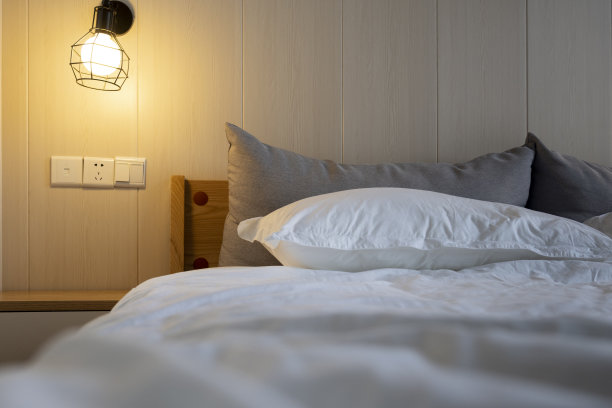 在柔和的灯光下，一个舒适的房间，一个舒适的床和床头柜图片下载