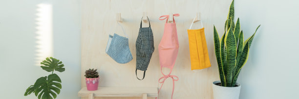 许多口罩挂在钩子上。丰富多彩的面料颜色和图案的选择在商店出售。全景横幅。图片下载