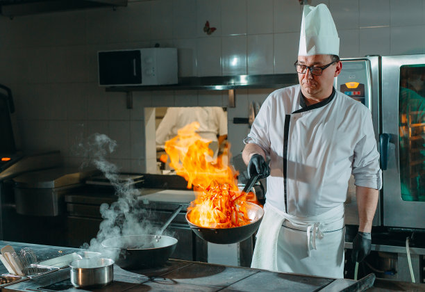 现代厨房。厨师在餐厅或酒店厨房的炉子上准备饭菜。厨房里的火。图片下载