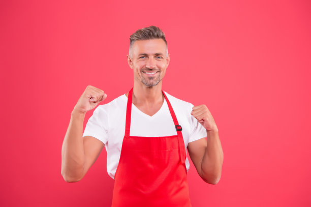 友好快乐的酒保。专业的清洁。家居与人的理念。热情自信的丈夫。厨房里穿着围裙的男人。帅气的看门人穿着清洁制服图片下载