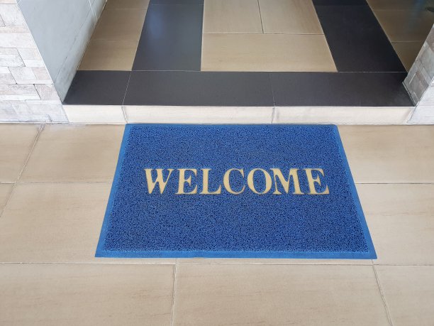 入口处的蓝色门垫上写着欢迎语图片下载