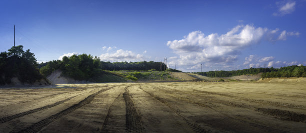 森林中被铲平的土地的全景景观，以多云的蓝天为背景图片下载