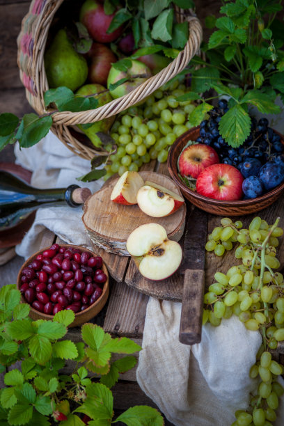 秋天的静物画。水果和浆果。一张木桌上放着苹果、葡萄、草莓、李子。乡村风格。闲置健康的维生素食品。水果的收成。老刀。篮子里的苹果图片下载