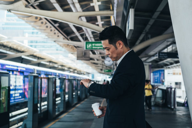 商人看他的手表，而等待在火车站库存照片图片下载