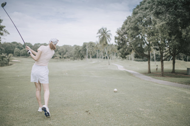亚洲华人女子高尔夫球手在高尔夫球场后视图开球图片下载