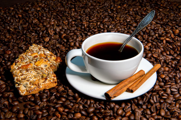 白色咖啡杯，肉桂棒和饼干在咖啡豆的背景-图像图片下载