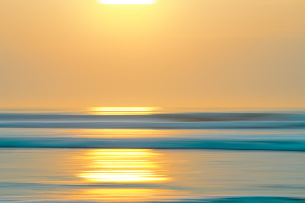 热带海滩日落。抽象海景背景与模糊平移运动。蓝色的水面和阳光反射图片下载