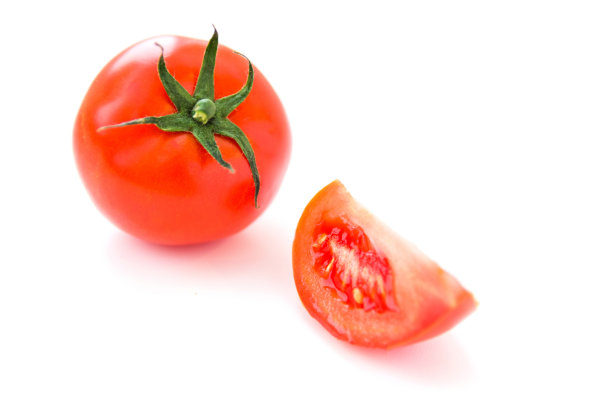美味的成熟的红番茄和一片它在白色的背景。侧视图。健康有机食品理念。农业和收获。图片下载