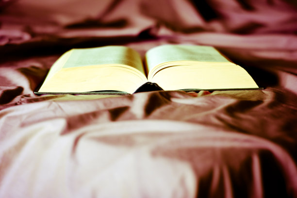 在床上的床单上有一本打开的书图片下载