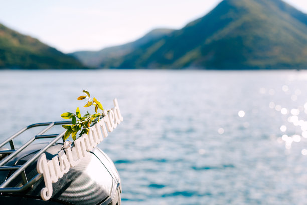 刚结婚的字母在摩托车后备箱。白色木制信件。黑山，佩拉斯特，一辆停在海滨的摩托车。欧洲蜜月旅行的概念。图片下载