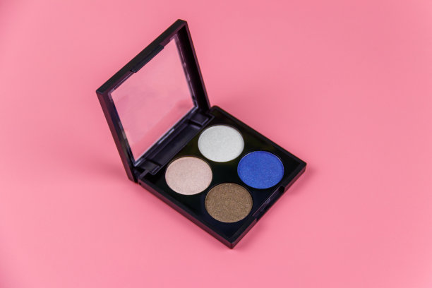 一套四个圆形的眼影在一个塑料黑色的盒子，在一个柔和的粉红色背景。平躺图片下载