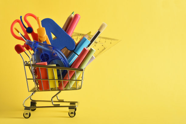 学校用品在购物车的黄色背景与复印空间图片下载
