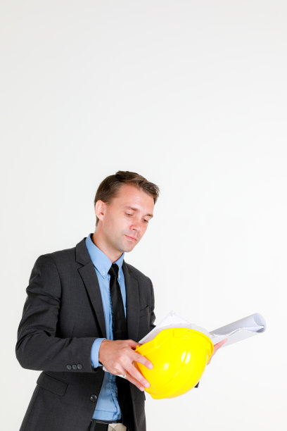 一名白种人建筑工程师戴着安全帽看建筑平面布置图的肖像图片下载