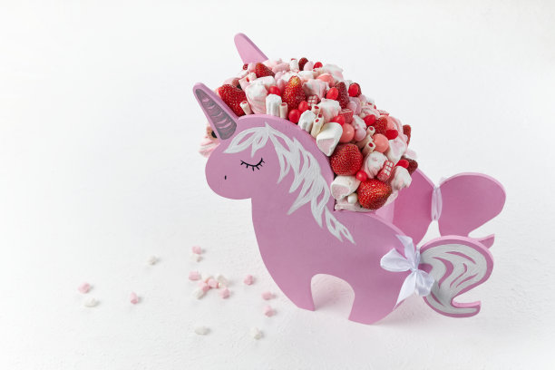 一个漂亮的独角兽形状的盒子，里面装满了成熟的草莓和糖果图片下载