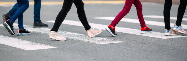 学童戴着医用口罩过马路。孩子们去上学。图片下载