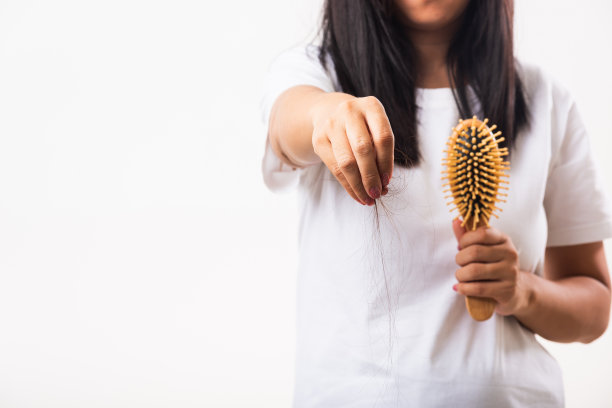 女人软弱的头发，她拿着发刷，用梳子梳理受损的长发，她从梳子上拉掉掉的头发图片下载