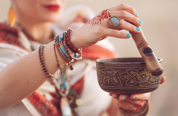 的概念。女子在打藏碗。日落时分，一名孕妇在野外做瑜伽图片下载