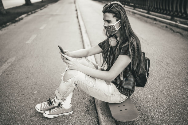 坐在滑板上玩手机的女人图片下载