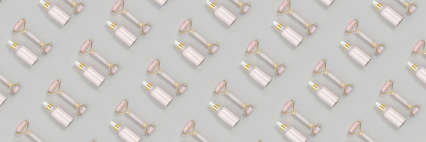 化妆品的模式。水晶玫瑰石英面部滚轮，抗衰老胶原蛋白，血清在玻璃瓶灰色背景。面部按摩自然提升，美容概念俯视图平躺横幅图片下载