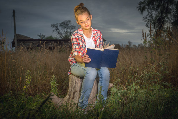 一个女孩在黄昏时分看书。图片下载