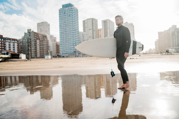 冲浪者拿着冲浪板站在海里。图片下载