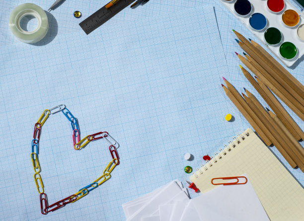 文具架上的蓝色坐标纸。颜料、铅笔、记事本、纸和别针制成的心。最喜欢的商务。最喜欢的爱好。为文本复制空间。图片下载