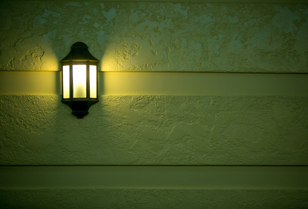 背景。绿色墙上的一盏几何形状的燃烧着的灯。图片下载