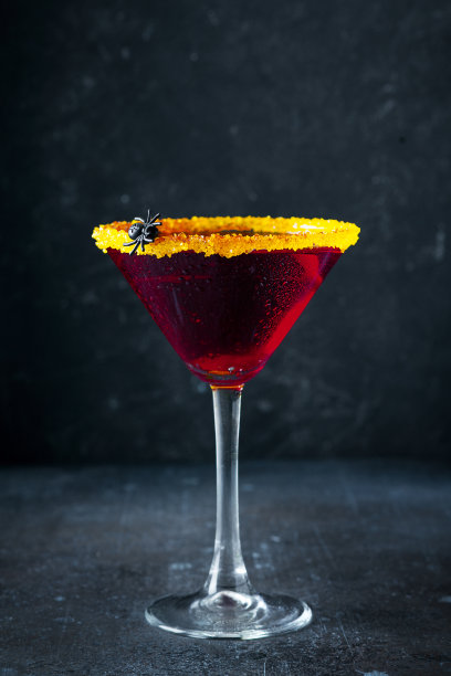 万圣节鸡尾酒黑寡妇与红色饮料的玻璃在黑暗的背景图片下载