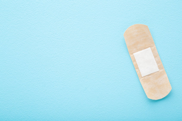 新的粘合绷带在浅蓝色的桌子背景。柔和的颜色。医学概念。特写镜头。文本的空位置。自顶向下的观点。图片下载