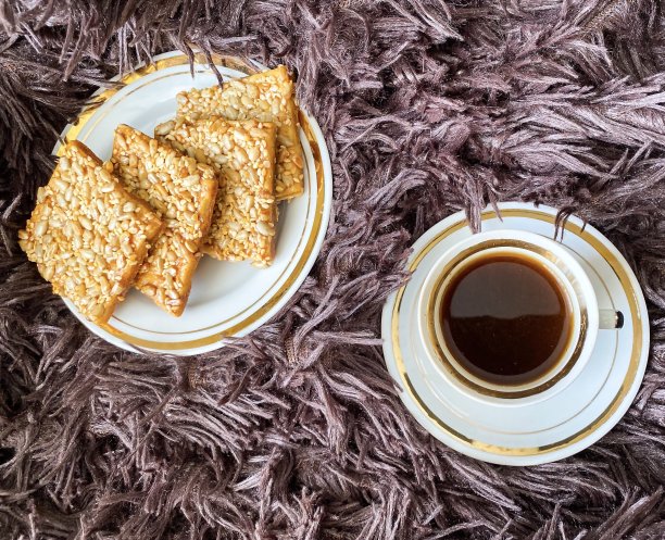 新鲜煮好的芳香提神的咖啡和床上的麦片饼干。图片下载