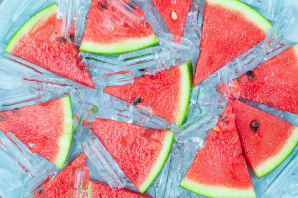 蓝色木桌上放着几块西瓜和冰块，俯视图。美味的甜点。图片下载
