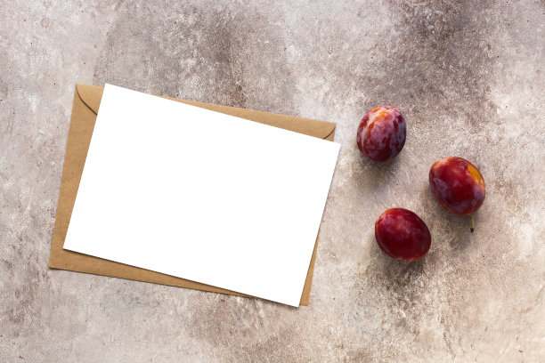 空白白纸模型与信封和新鲜李子。米色背景纹理。名片模板。俯视图，平放。图片下载