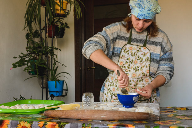 美丽的女人在家里的厨房里准备饺子，土豆饺子。图片下载