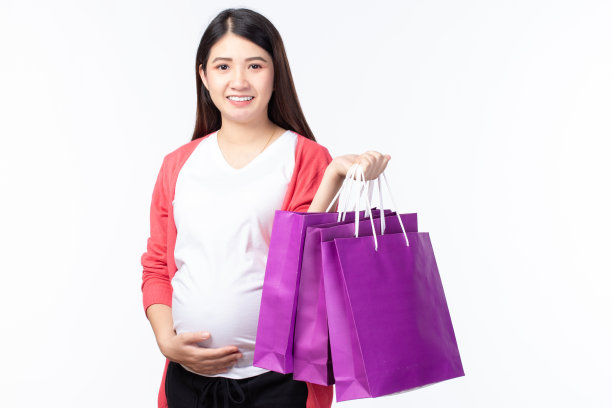 肖像快乐的年轻孕妇购物袋和触摸她的大肚子孤立在白色的背景。怀孕的购物理念。图片下载